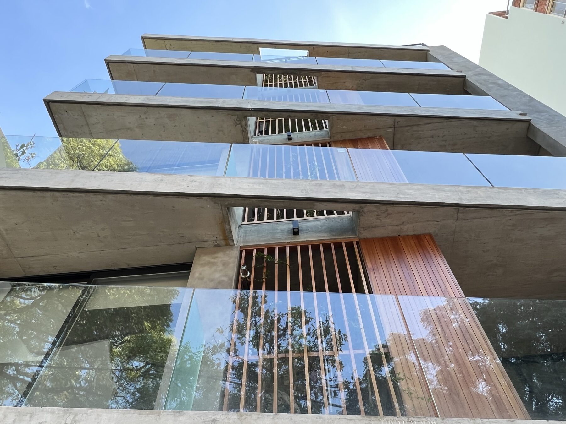 concrete and glass balconies with wooden screens seen from below