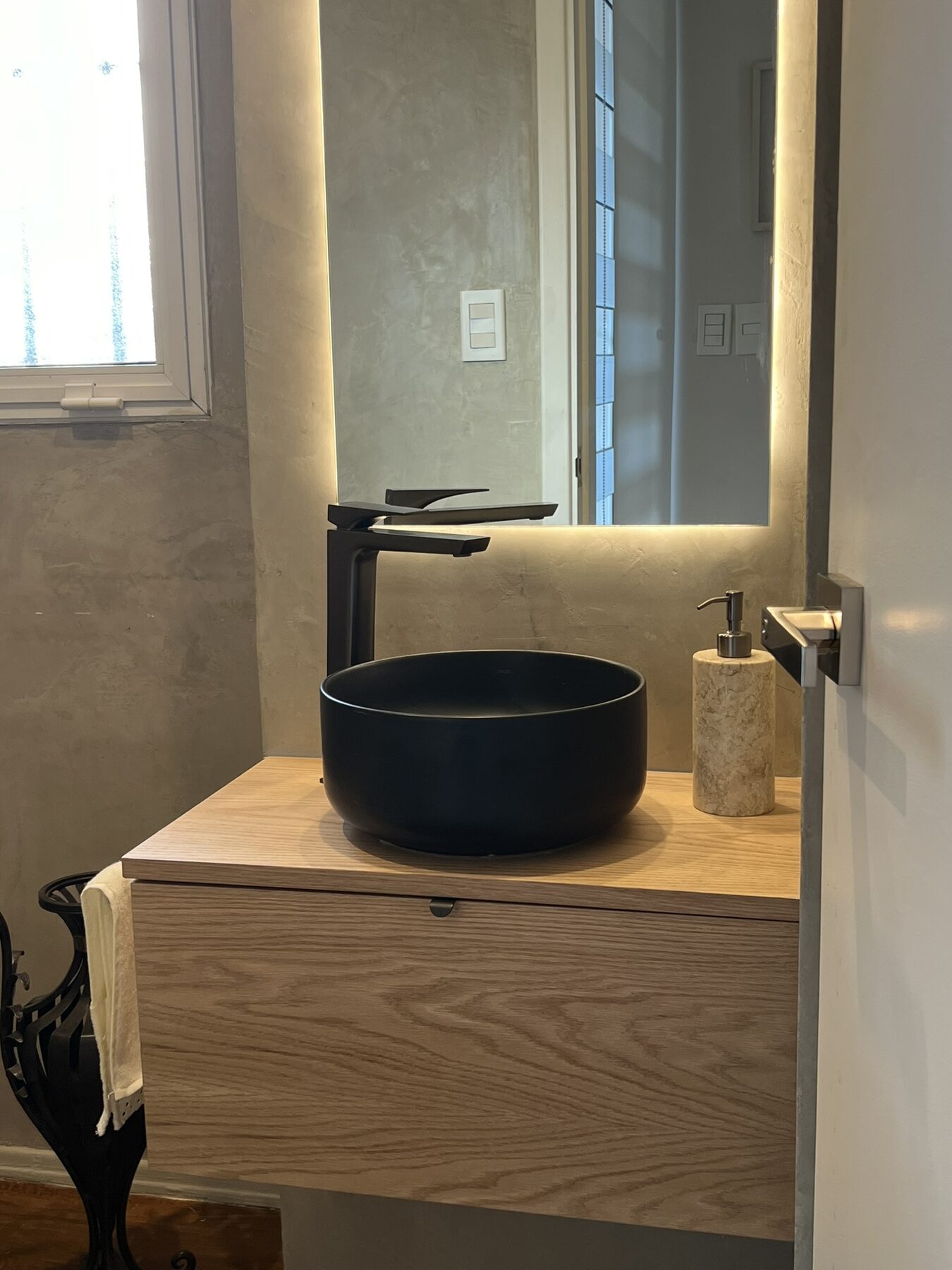 baño con lavatorio negro sobre mueble de roble