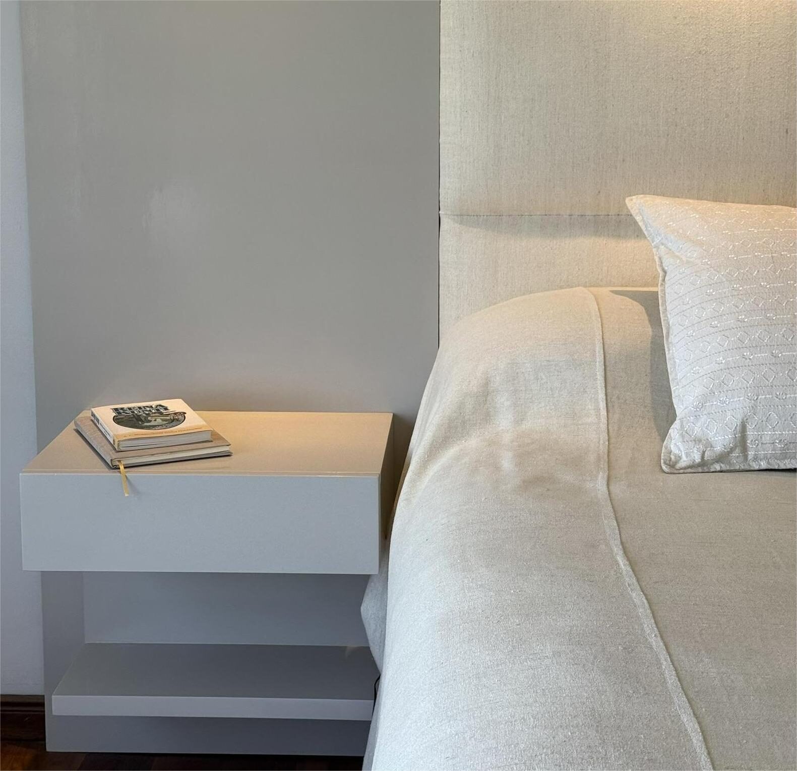 white nightstand next to the bed with linen bedding
